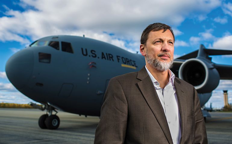 Tony Caruso, Director of Bangor International Airport, Stands in front of plane on tarmac of airport