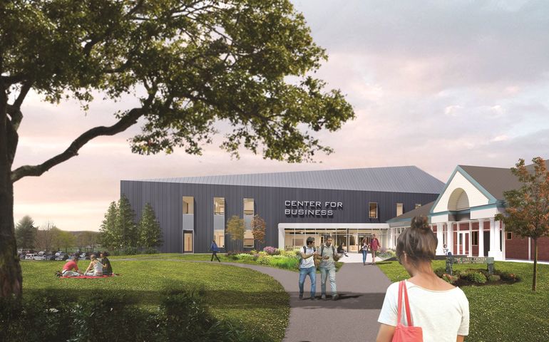 A drawing of the new project shows students walking on pathways and sitting on patches of grass under the shade of large trees. A modern-looking gray building features a sign affixed to the exterior above a large glass entryway. The sign reads “Center for Family Business” in all capital modern letters. In front of this gray building is the current Dyke Center for Family Business, a red brick building with a covered patio entry, with large white columns holding up a peaked white ceiling.